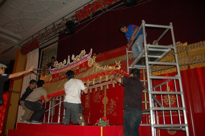 A group of individuals collaboratively setting up an ornate decorative structure indoors