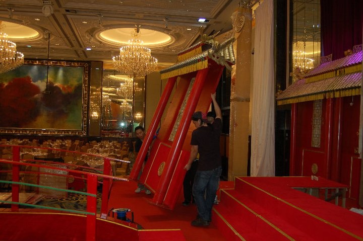 A stage setup featuring an intricately designed red and gold structure with elegant carvings