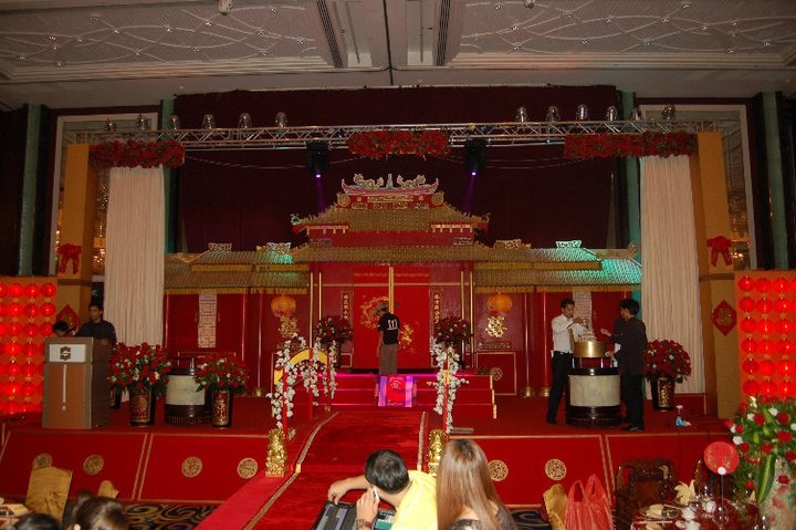 A ceremonial setup for a chinese wedding featuring a grand, ornate structure with intricate gold detailing and red accents