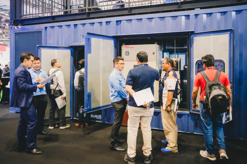 MHI-ESA staff members providing a technical demonstration of the MGS2500R containerized generator at a trade show.