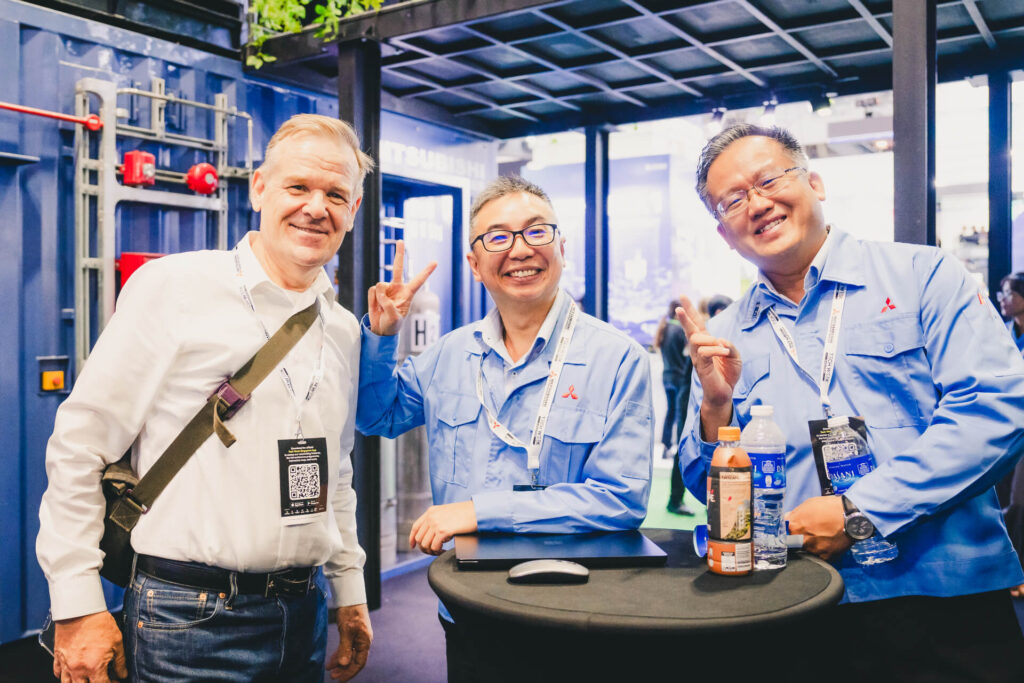Mitsubishi Heavy Industries (MHI-ESA) staff and a visitor sharing a joyful moment at the Data Centre World Asia 2025 booth