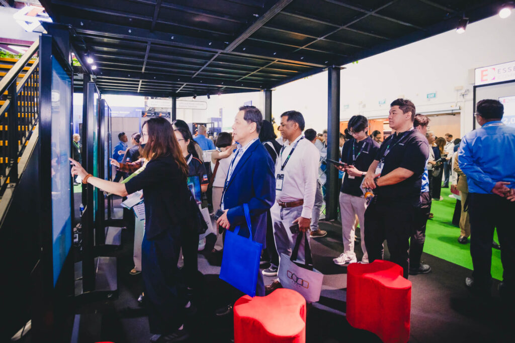 Visitors engage with interactive digital touchscreens at the Mitsubishi Heavy Industries innovation booth during a trade show