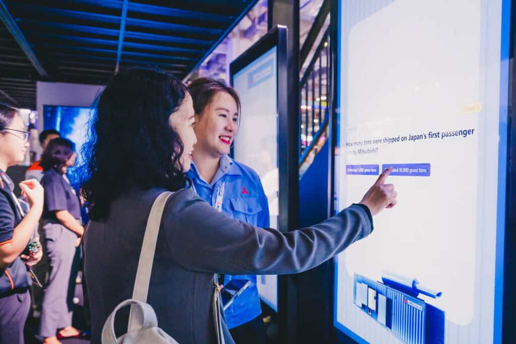 A visitor participates in an interactive history quiz at the Mitsubishi Heavy Industries booth during a trade show.